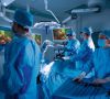 Vier Menschen mit blauen OP-Kitteln, Maske und OP-Haube stehen in einem OP-Saal. Operationssaal für die minimalinvasive Chirurgie.