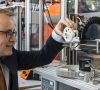 Tom Krause, Produktmanager Iglidur Tribo-Filament bei Igus, Köln, prüft einen fertig montierten 3D-Drucker. Die weißen Zahnräder sind im FDM-Verfahren entstanden.