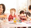 Frau mit drei Kindern an einem gedeckten Tisch mit Eierbecher und Tellern aus TPE.