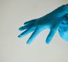 Ein Mensch zieht sich blaue Gummihandschuhe an